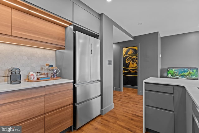 kitchen with stainless steel fridge, light hardwood / wood-style flooring, and backsplash