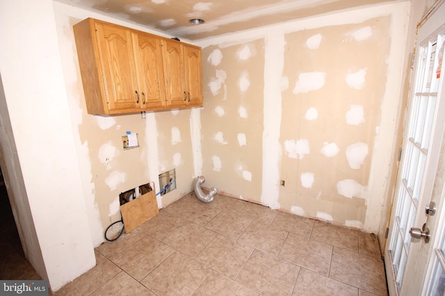 clothes washing area featuring cabinets, washer hookup, and light tile patterned floors