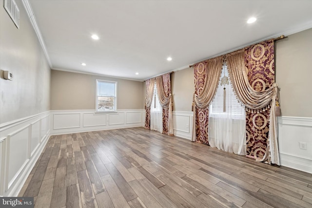 spare room featuring wood-type flooring and crown molding