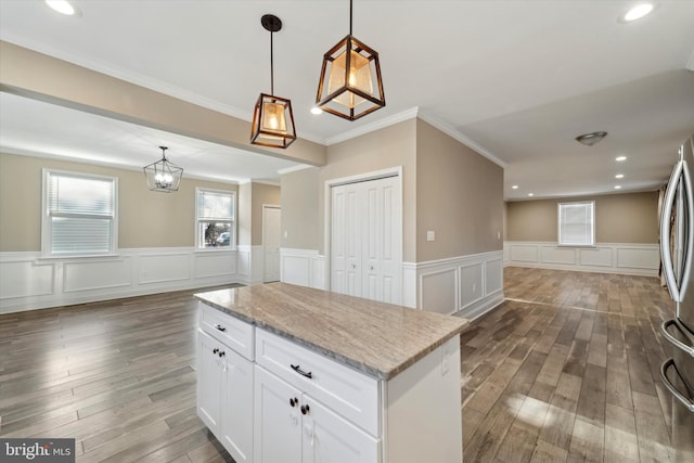 kitchen featuring light stone counters, hanging light fixtures, dark hardwood / wood-style floors, a kitchen island, and white cabinets