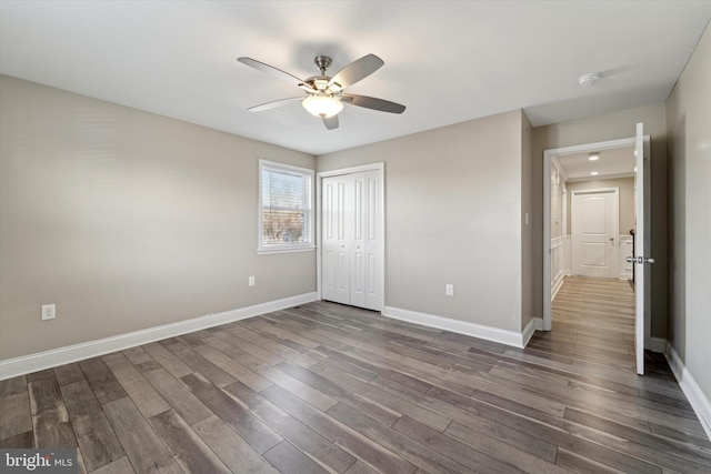 unfurnished bedroom featuring ceiling fan, dark hardwood / wood-style floors, and a closet