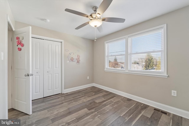 unfurnished bedroom featuring hardwood / wood-style floors, ceiling fan, and a closet