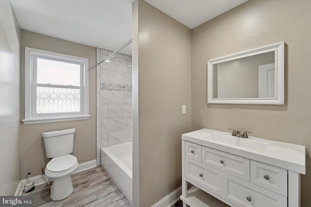 full bathroom with vanity, hardwood / wood-style floors, tiled shower / bath, and toilet