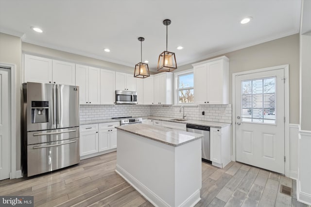 kitchen featuring a kitchen island, white cabinets, hanging light fixtures, light hardwood / wood-style floors, and stainless steel appliances