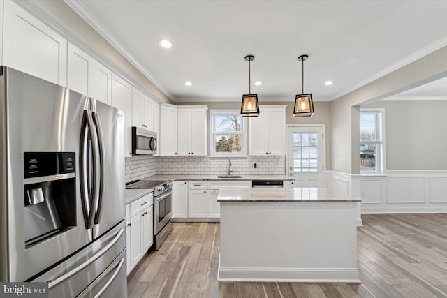 kitchen featuring appliances with stainless steel finishes, decorative light fixtures, white cabinetry, sink, and light stone countertops