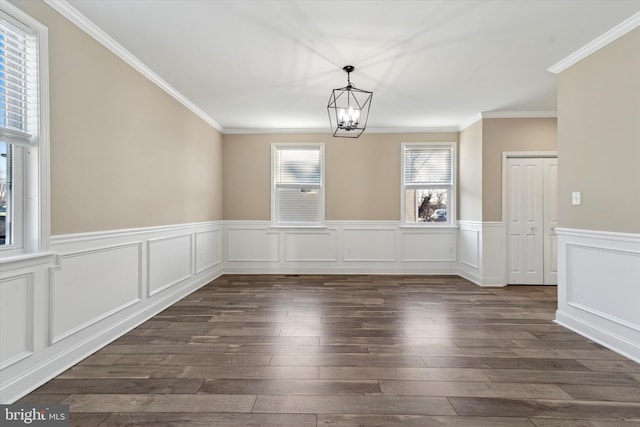 unfurnished dining area with a notable chandelier, dark wood-type flooring, and ornamental molding