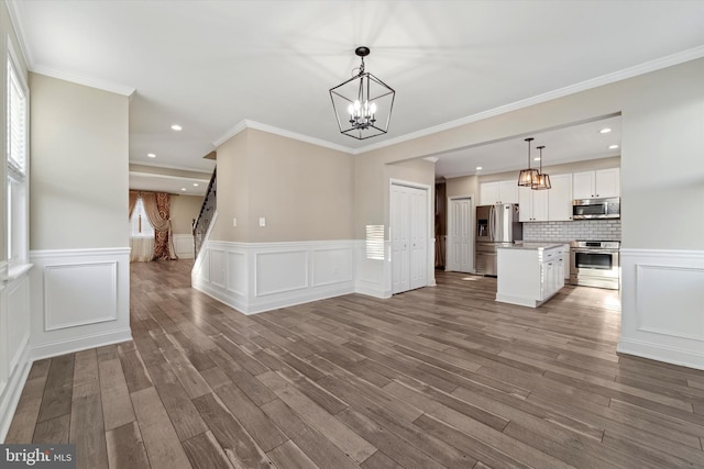 kitchen featuring white cabinetry, decorative light fixtures, a center island, dark hardwood / wood-style flooring, and stainless steel appliances