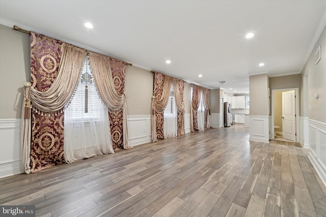 unfurnished living room featuring ornamental molding and light wood-type flooring