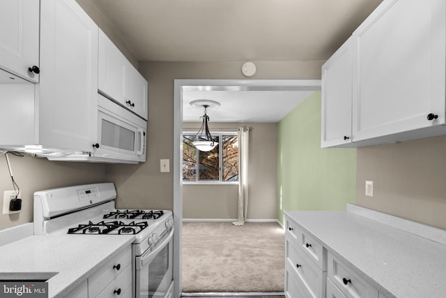 kitchen featuring pendant lighting, white cabinetry, light stone counters, light carpet, and white appliances