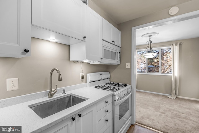 kitchen featuring white cabinetry, white appliances, light stone countertops, and sink