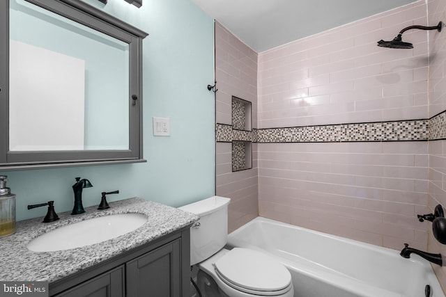 full bathroom with vanity, tiled shower / bath combo, and toilet