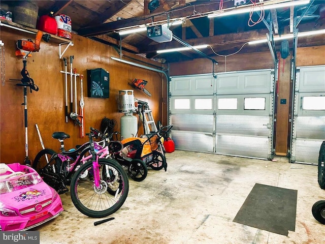 garage with a garage door opener and wood walls