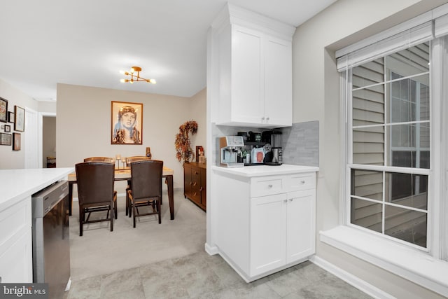 kitchen featuring white cabinetry, dishwasher, light carpet, and backsplash