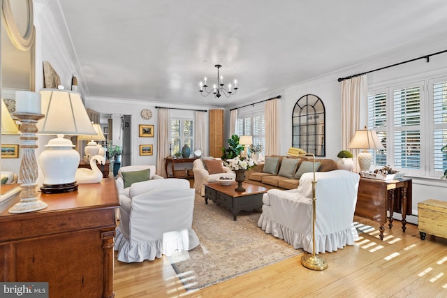 living room featuring an inviting chandelier, crown molding, and light hardwood / wood-style flooring