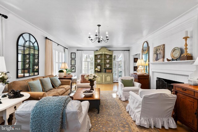 living room with hardwood / wood-style floors, crown molding, a fireplace, and a notable chandelier