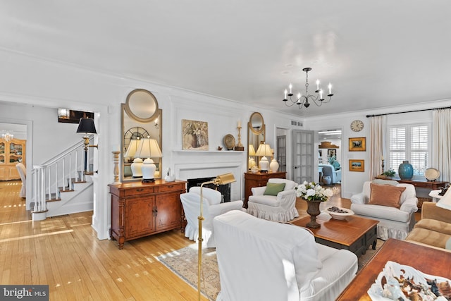 living room featuring an inviting chandelier, light hardwood / wood-style flooring, and ornamental molding