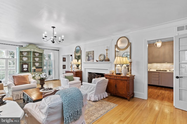 living room with ornamental molding, a chandelier, and light wood-type flooring