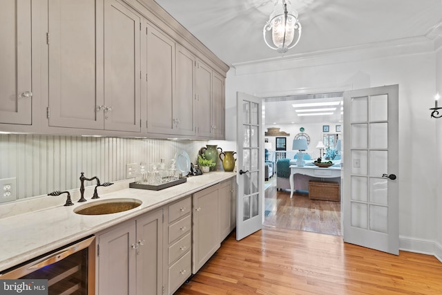 kitchen featuring gray cabinets, sink, beverage cooler, light hardwood / wood-style floors, and crown molding