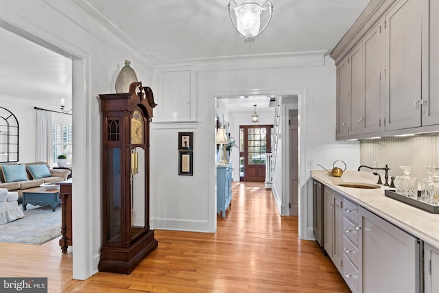 kitchen featuring ornamental molding, gray cabinets, sink, and light hardwood / wood-style flooring