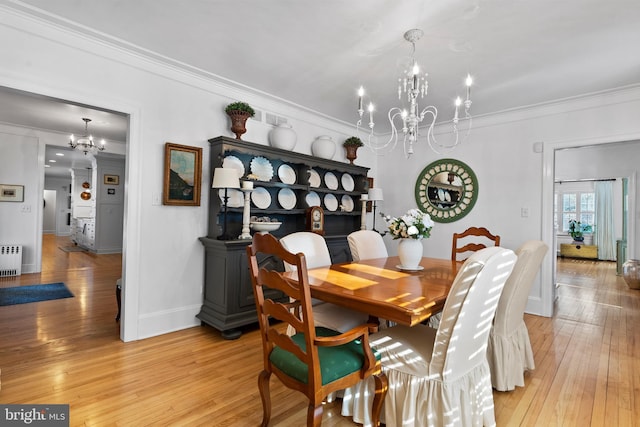 dining room with a notable chandelier, crown molding, radiator, and light wood-type flooring