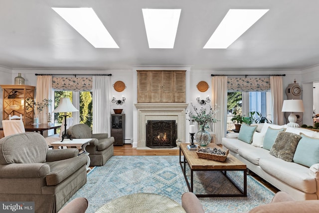 living room with ornamental molding, plenty of natural light, a baseboard heating unit, and light hardwood / wood-style floors