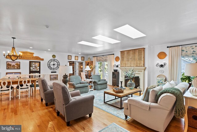 living room featuring crown molding, an inviting chandelier, light wood-type flooring, and a skylight