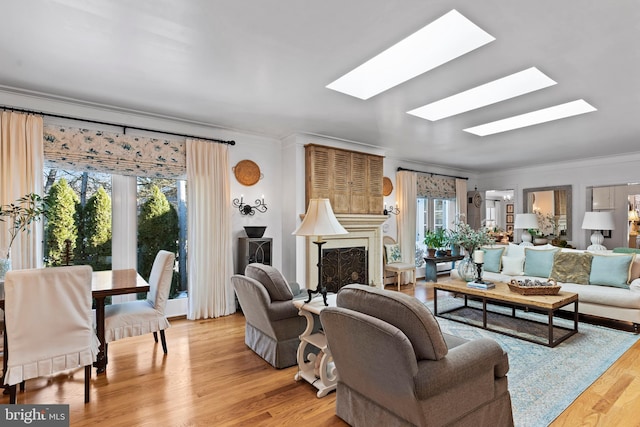 living room featuring ornamental molding, a skylight, and light wood-type flooring