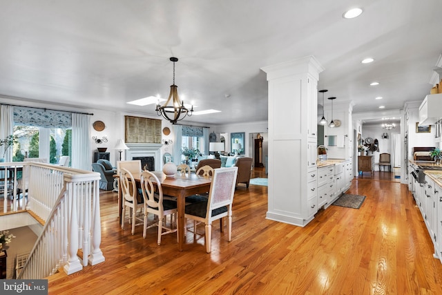 dining space featuring ornamental molding, sink, a chandelier, and light hardwood / wood-style floors