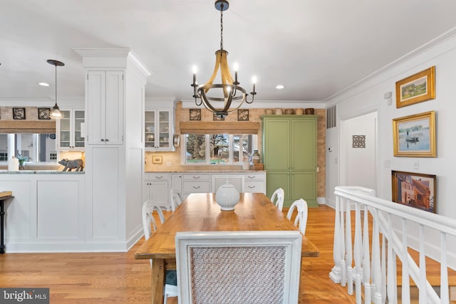 dining space featuring crown molding, light hardwood / wood-style floors, and a chandelier