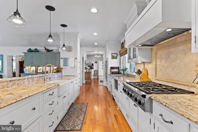 kitchen with pendant lighting, sink, white cabinets, and premium range hood