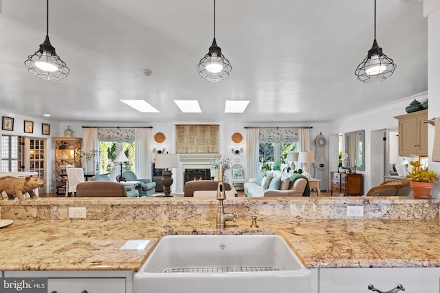 kitchen with ornamental molding, sink, and hanging light fixtures