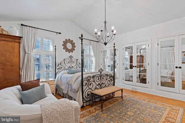 bedroom featuring lofted ceiling, a chandelier, hardwood / wood-style flooring, access to outside, and french doors