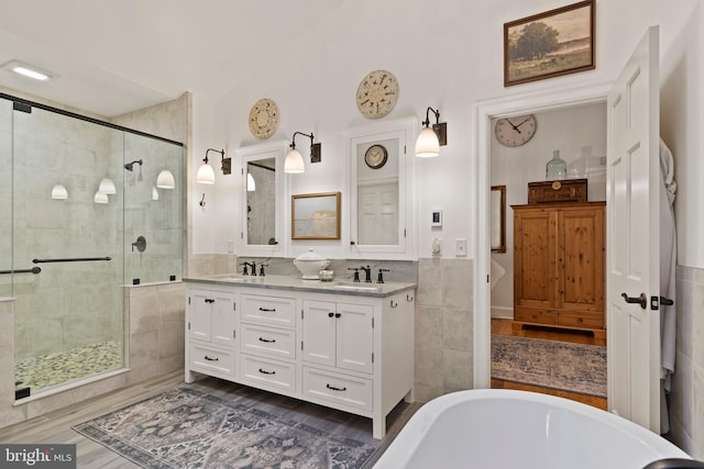 bathroom with vanity, shower with separate bathtub, and tile walls