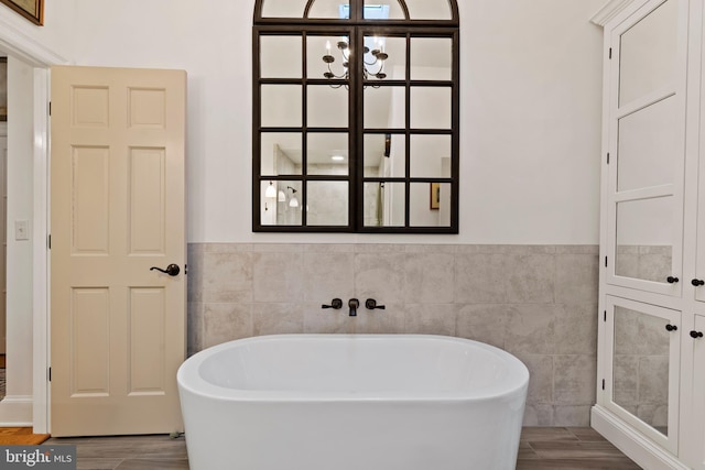 bathroom featuring hardwood / wood-style flooring, a tub, and tile walls