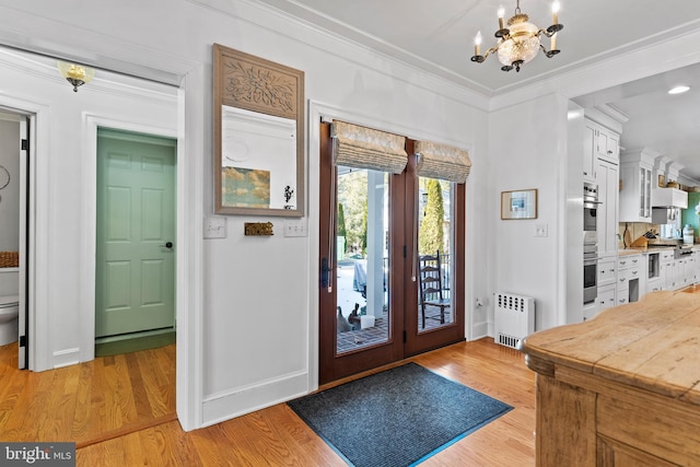 foyer entrance featuring ornamental molding, radiator, a notable chandelier, and light hardwood / wood-style flooring