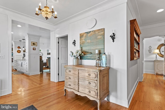 corridor featuring an inviting chandelier, ornamental molding, and light wood-type flooring