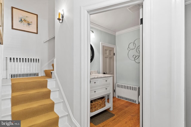 stairway featuring hardwood / wood-style flooring, crown molding, and radiator heating unit