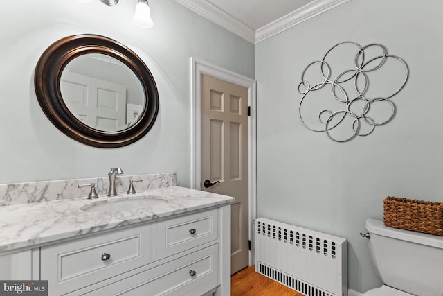 bathroom featuring toilet, wood-type flooring, ornamental molding, vanity, and radiator