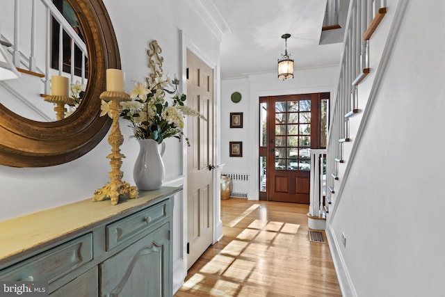 foyer entrance with ornamental molding, radiator, and light hardwood / wood-style flooring