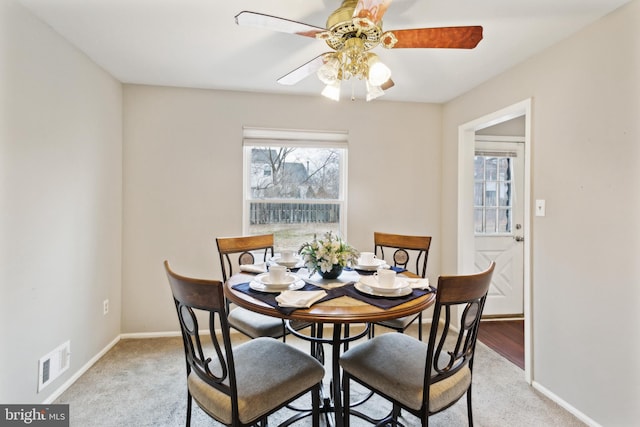 dining area with ceiling fan and light colored carpet