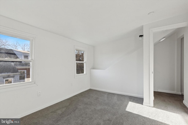 unfurnished room with dark carpet and a wealth of natural light