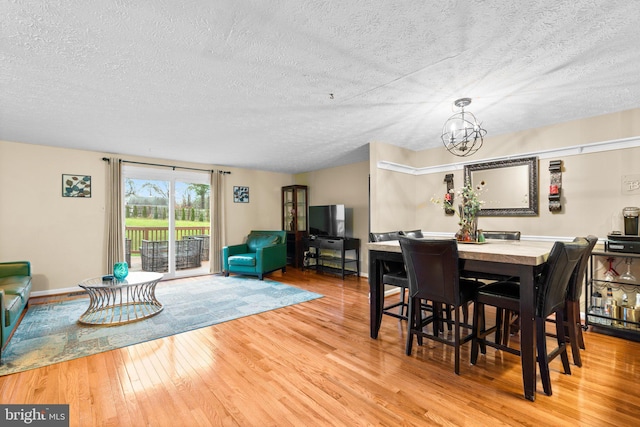 dining room featuring a notable chandelier, light hardwood / wood-style floors, and a textured ceiling