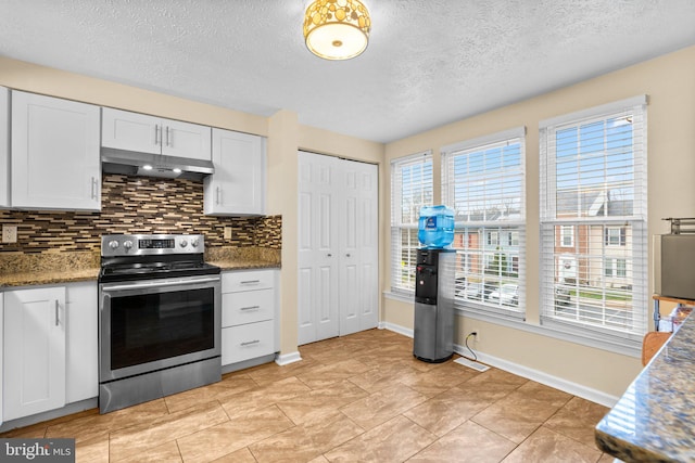 kitchen featuring light tile patterned flooring, tasteful backsplash, dark stone countertops, electric range, and white cabinets