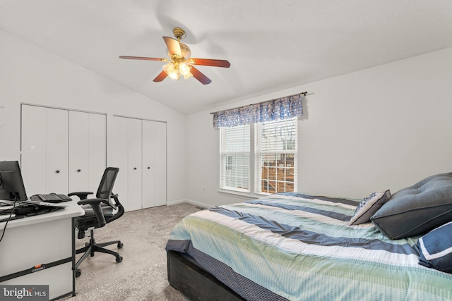 bedroom featuring multiple closets, ceiling fan, vaulted ceiling, and light carpet