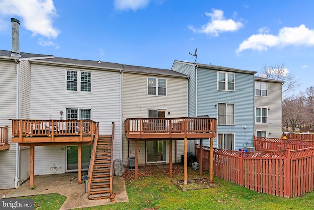 rear view of house featuring a wooden deck and a lawn