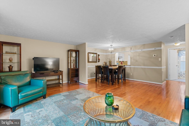 living room featuring hardwood / wood-style flooring, a chandelier, and a textured ceiling