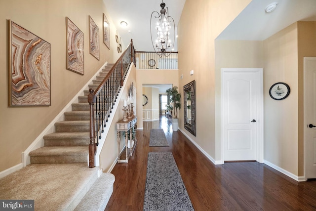 entrance foyer with dark wood-type flooring, a notable chandelier, and a towering ceiling