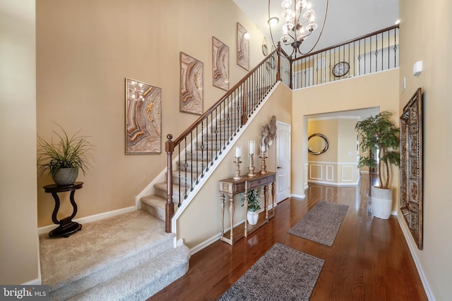 entryway with dark wood-type flooring, a notable chandelier, and a towering ceiling