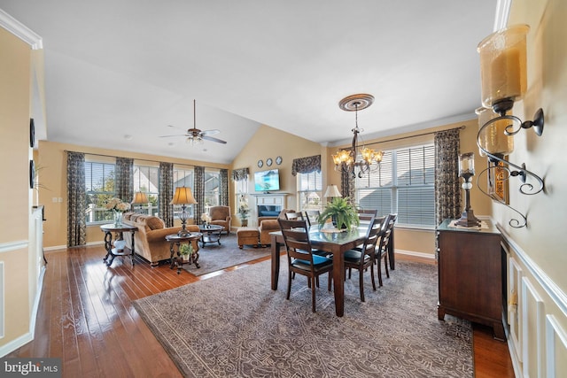 dining space with ceiling fan with notable chandelier, vaulted ceiling, and dark hardwood / wood-style floors