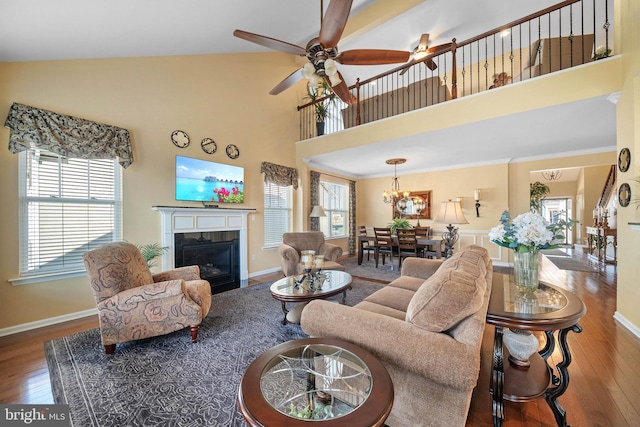 living room with ceiling fan, wood-type flooring, ornamental molding, and a high ceiling